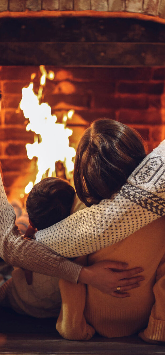 Family sitting together in front of a fireplace with a Christmas tree in the background