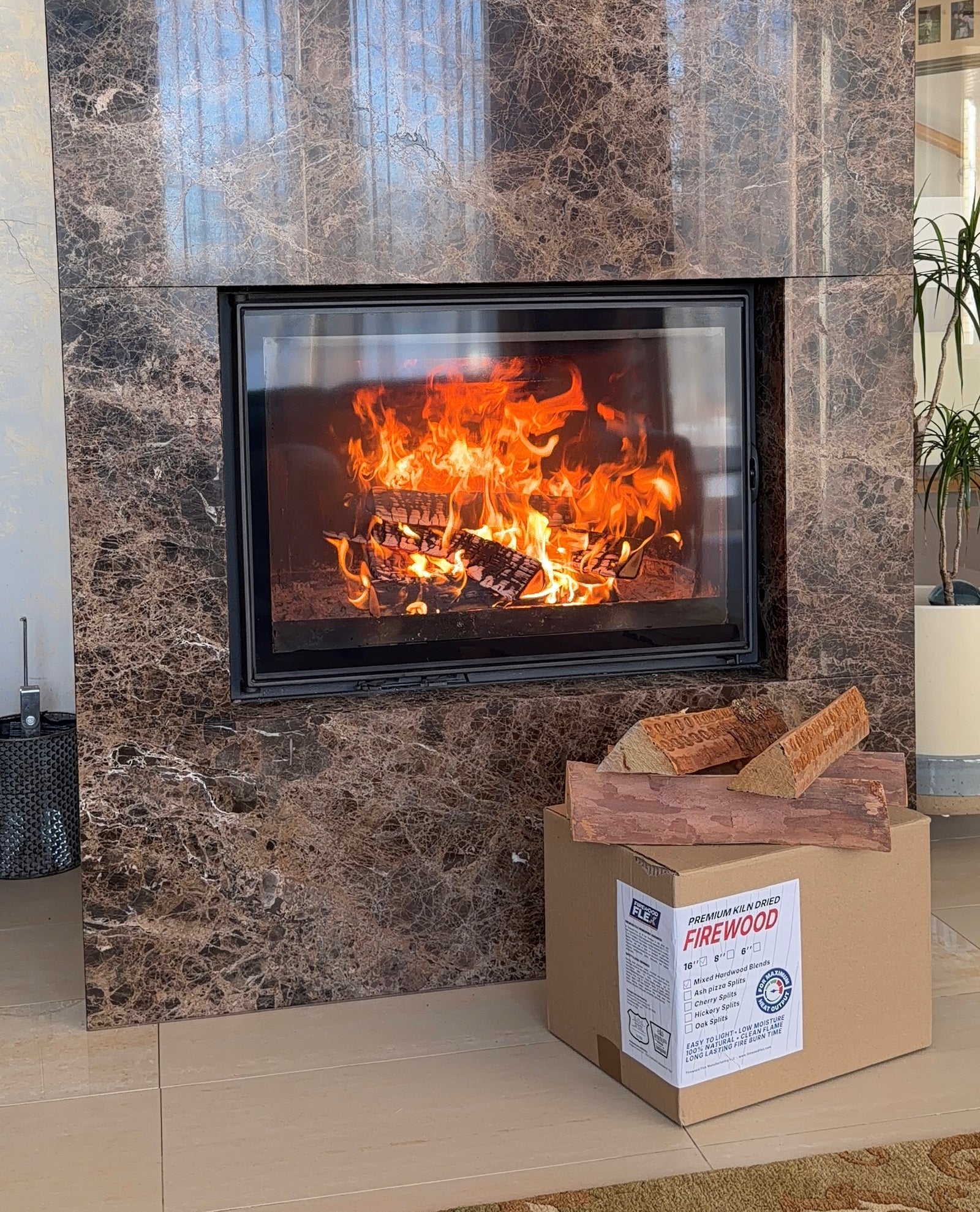 Marble fireplace with a fire burning inside, a kiln dried firewood cardboard box on the floor